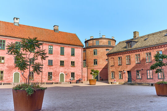 Landskrona, Sweden - 08 August 2025: View of the historic Landskrona Citadel's robust red brick buildings under a serene blue sky, framed by lush greenery.