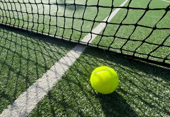Naklejka premium Ball Beside Tennis or Padel Net on Green Artificial Turf Court with White Line, Outdoor Sports Background with Copy Space