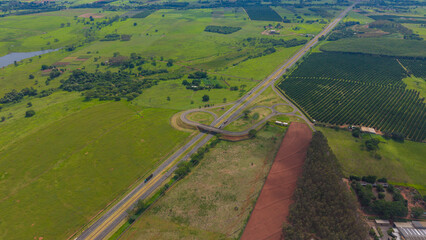 Aerial view of a serene landscape with a winding road and lush green fields © Felippe Lopes