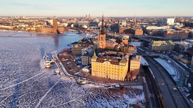 Riddarholmen island in Stockholm, Sweden, showing the historic church spire, surrounding city architecture, and partially frozen water during winter.