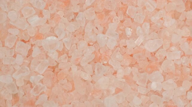 Zoom frame pink salt crystals in plate, rotate. Natural rock salt of pinkish
