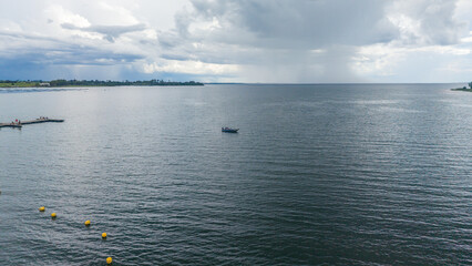 A serene ocean landscape with a small boat on the water under a cloudy sky © Felippe Lopes
