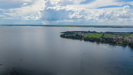 Fototapeta premium Aerial view of a serene lake with a small town on the shore under a cloudy sky