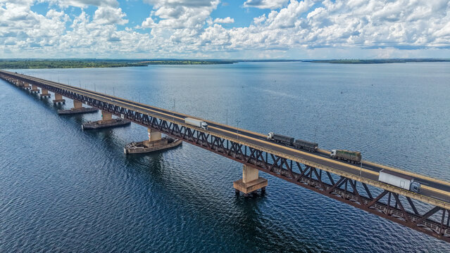 An aerial view of a long bridge spanning across a large body of water with boats underneath
