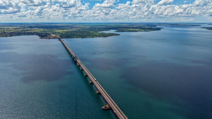 Fototapeta premium An aerial view of a long bridge extending over a vast body of water under a cloudy sky