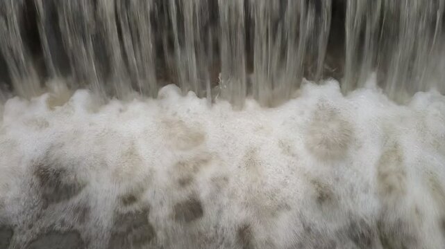 Overflowing lake water flowing over dam spillway in full HD