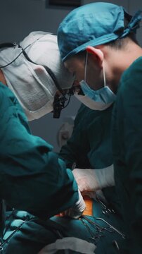 Surgical team working together during a medical operation. Sterile environment and focused teamwork inside a hospital operating room. Professional healthcare teamwork. Vertical shot
