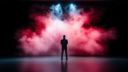 Fototapeta premium A powerful silhouette of a person stands against vibrant colored smoke and lights, creating a dramatic ambiance that conveys mystery and introspection.