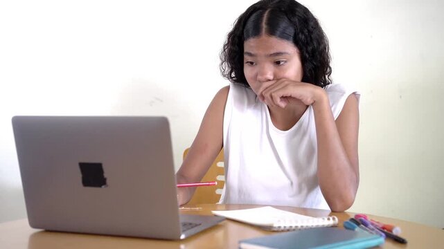 Asian girl studying online feeling thoughtful and then having a moment of realization and success