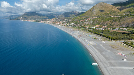 Obraz premium Aerial view of the long beach of Praia a Mare, located in the province of Cosenza, Calabria, southern Italy. Panorama of a vast grey pebble coastline meeting the deep blue Tyrrhenian sea.