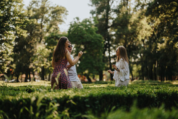 Fototapeta premium Three friends enjoy a playful moment in a park, chatting and laughing. The group stands on grass under trees, captured in natural daylight.