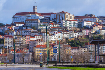 Hillside cityscape of Coimbra featuring a grand white building complex with a clock tower atop a hill