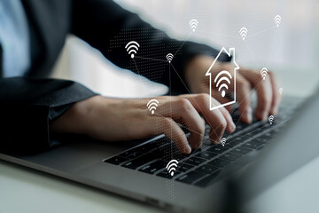Naklejka premium A professional man types on a laptop, highlighting the integration of smart home technology symbols, showcasing the blend of modern work and advanced connectivity. Gantry