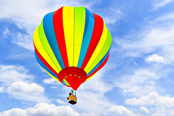 Obraz premium Colorful hot air balloon flying over blue sky with white clouds