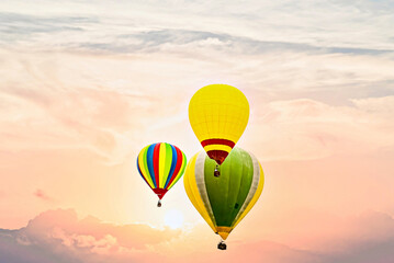 Obraz premium Colorful hot air balloon flying under orange sunset sky 