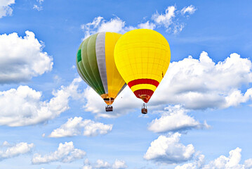 Colorful hot air balloon flying over blue sky with white clouds