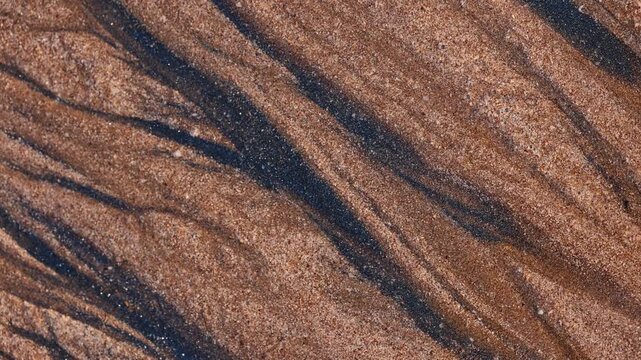 Magical with Black Sand Beaches on multicolored Hormuz Island, Iran. The dark sand from heavy minerals such as hematite, ilmenite, and magnetite, creating striking textures along the shoreline.