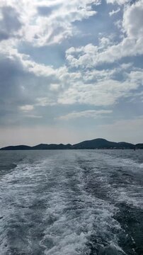 ferry departing from lan island, cutting through calm waters with mountainous backdrop