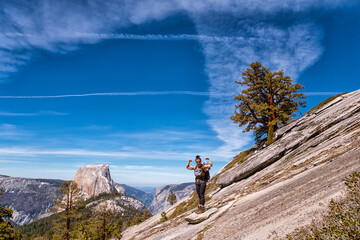 A woman is standing on a rocky mountain top, posing for a picture