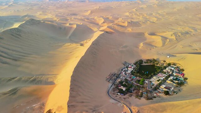 Aerial drone view of a desert landscape with the Huacachina oasis, sand dunes and the city of Ica. Peru	
