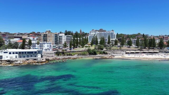 flying to Ross Jones Rockpool with a right pan to Coogee Beach, where many people sunbathing at the beach and Sydney cityscape in background, located in Coogee Bay, Pacific Ocean, Australia - 4k video
