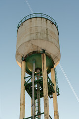 A water tower illuminated by the rays of the evening sun. A tall water tower against a blue sky.