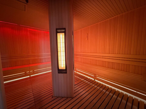 Infrared sauna cabin with central heaters and wooden floor. Heat therapy, recovery session, wellness routine, detox process, relaxation environment