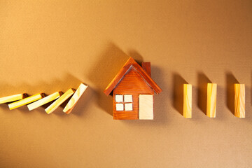 Wooden toy house and dominoes on a brown background.