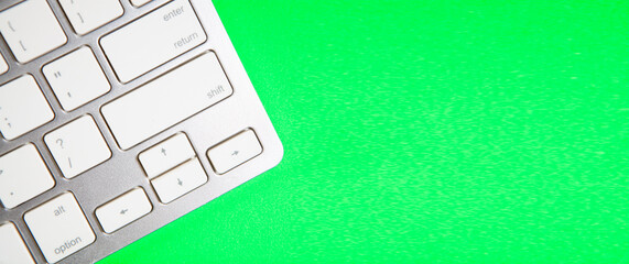 Close up of white computer keyboard on green background with copy space.