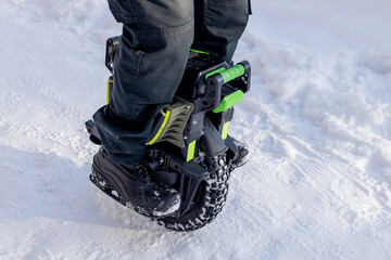Person riding electric unicycle monowheel self-balancing personal transportation device on snowy winter terrain showing alternative eco-friendly urban mobility technology outdoor recreation activity © MarijaBazarova