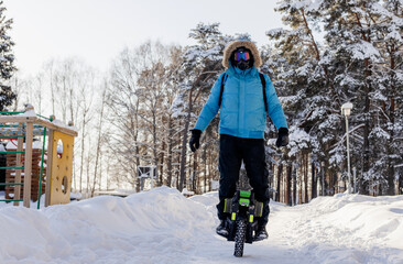 Person riding electric unicycle monowheel self-balancing personal transportation device on snowy winter terrain showing alternative eco-friendly urban mobility technology outdoor recreation activity © MarijaBazarova