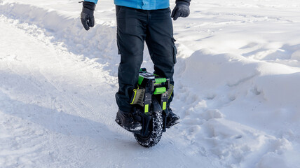 Person riding electric unicycle monowheel self-balancing personal transportation device on snowy winter terrain showing alternative eco-friendly urban mobility technology outdoor recreation activity © MarijaBazarova