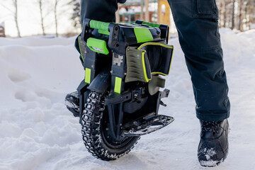 Person riding electric unicycle monowheel self-balancing personal transportation device on snowy winter terrain showing alternative eco-friendly urban mobility technology outdoor recreation activity © MarijaBazarova