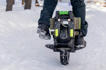 Person riding electric unicycle monowheel self-balancing personal transportation device on snowy winter terrain showing alternative eco-friendly urban mobility technology outdoor recreation activity © MarijaBazarova
