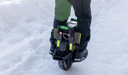 Person riding electric unicycle monowheel self-balancing personal transportation device on snowy winter terrain showing alternative eco-friendly urban mobility technology outdoor recreation activity © MarijaBazarova