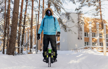 Person riding electric unicycle monowheel self-balancing personal transportation device on snowy winter terrain showing alternative eco-friendly urban mobility technology outdoor recreation activity © MarijaBazarova
