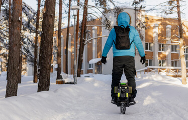 Person riding electric unicycle monowheel self-balancing personal transportation device on snowy winter terrain showing alternative eco-friendly urban mobility technology outdoor recreation activity © MarijaBazarova