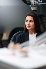 Thoughtful Caucasian Consultant In Clinic Setting, Seated With Folded Hands, Sharp Business Attire, Operatory