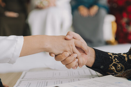 Groom Shaking Hands During Nikah Ceremony.A close-up of a groom's hand shaking the hand of the officiant or father (Wali) during the solemnization of marriage (Akad Nikah) in a Malay wedding.