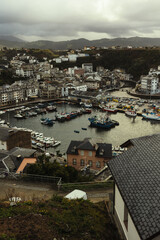 Fototapeta premium Fishing Port in a European Coastal Village Under Cloudy Skies and Dramatic Light