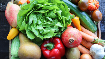 Organic vegetables from the garden - carrots, tomatoes, peppers, cucumbers, lettuce and fruits in wooden box . Raw healthy food concept. Top view