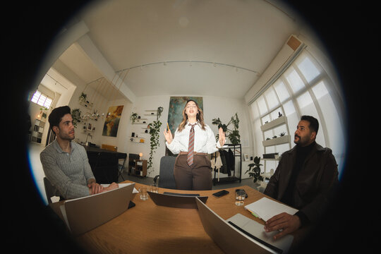 A woman presents an idea to two men during a business meeting in a modern office space.