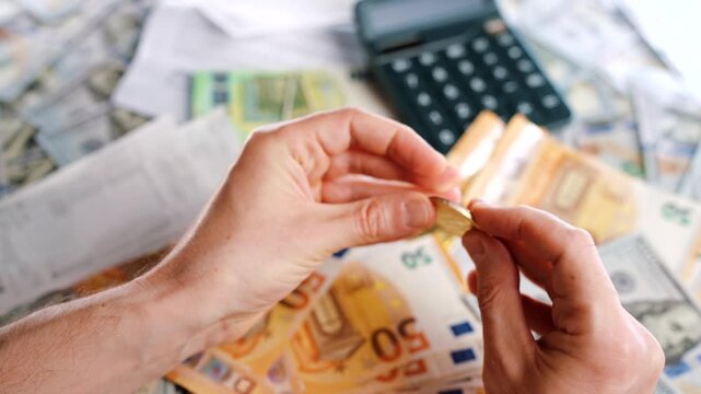 Hands shows silver and golden BTC bitcoin against the dollars and euros