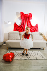 Obraz premium Moscow, Russia, 08.02.2026 Caucasian kid girl in cute dress jumping with heart balloon. Happy childhood and celebration concept for Mother Day and Valentine Day.