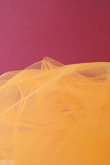 Bright orange tulle fabric on wine color background.  Abstract transparent material curve wave.