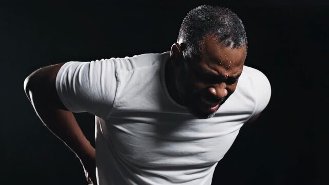 Man experiencing severe back pain and discomfort with strained facial expression and bent posture in distress