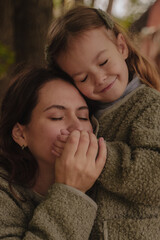 Mother's Day. Daughter and mother hug with closed eyes. Mom kisses her daughter's little palm. A warm and loving relationship between the child and the parent. Warm and sincere emotions.