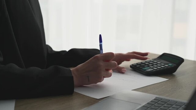 A businesswoman uses a calculator in a bright office.
A female financier calculates profits on a calculating machine.