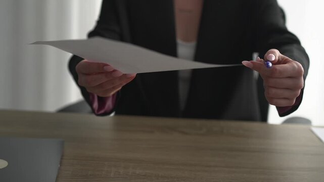 A secretary signs documents in an office.
Paperwork in the office.
A businesswoman holding documents.
Employment contract