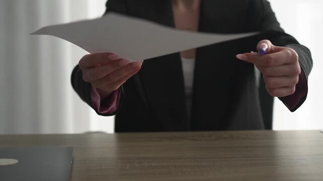 A female boss hands over documents for signing.
Paper contract. Signing documents.